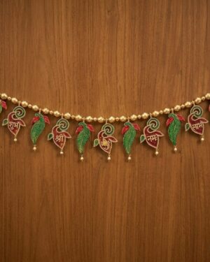 Vibrant multicolor Meenakari thoranam with Shubh Labh inscriptions and gold beads on a wooden background.