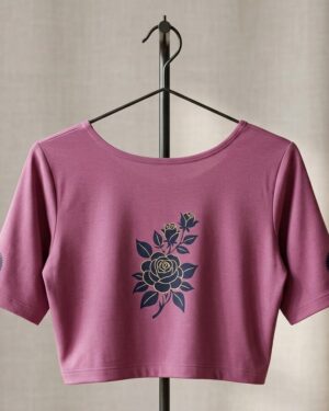 A mauve-rose short-sleeve with a navy blue and gold rose graphic printed in the center, hanging on a black metal rack