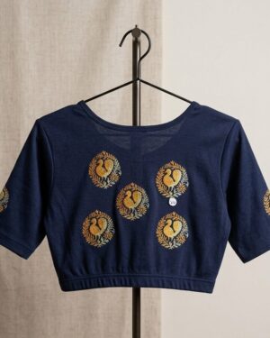 A navy blue Stretchable blouse with short sleeves hanging on a black metal stand, showcasing five circular gold Printed bird motifs on the back.