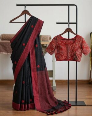 A black and red Khadi cotton saree with embroidered heart motifs displayed on a hanger alongside a red Kalamkari blouse.
