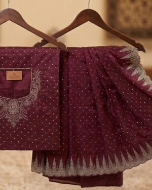 A rich wine-maroon saree with delicate shimmering accents and an intricate scalloped border, displayed on a wooden hanger next to its matching blouse piece which showcases a detailed Stone work neck design intended for the back.