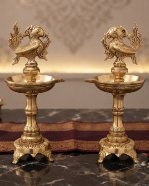 Handcrafted traditional 2 Exquisite Brass Bird Deepam placed on a polished marble surface with a festive silk runner background.