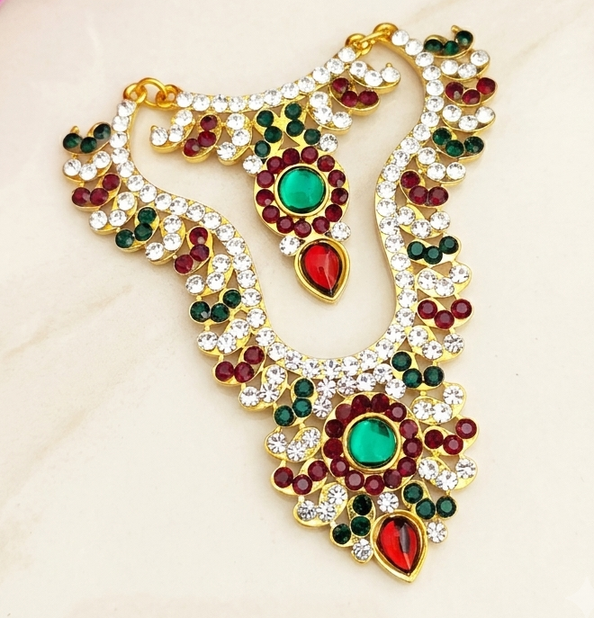 An opulent Exquisite god idol chain necklace sparkling with brilliant white stones and vibrant ruby-emerald accents, displayed flawlessly on a neutral surface.